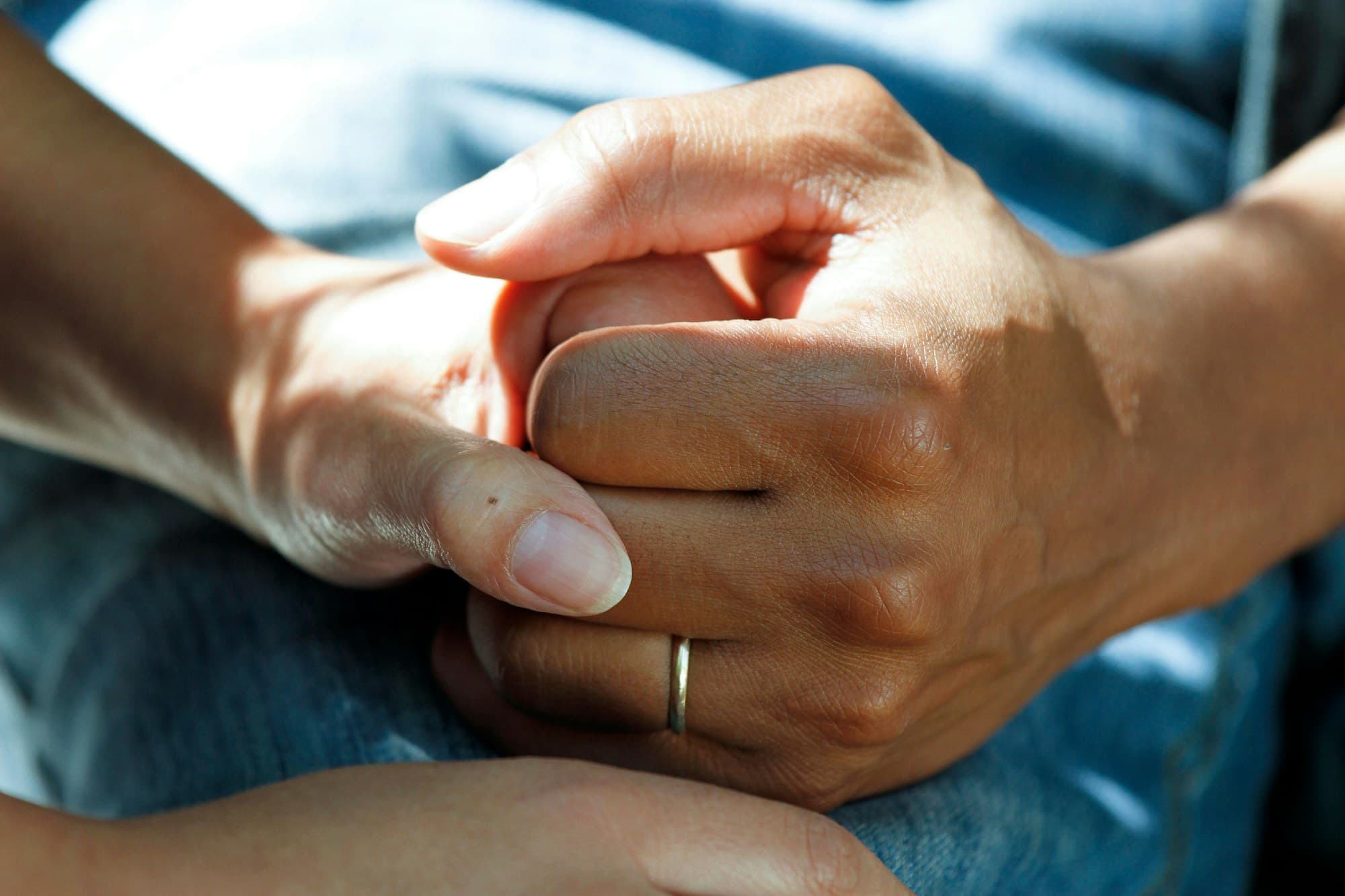 A caregiver gently holding an older adult’s hands
